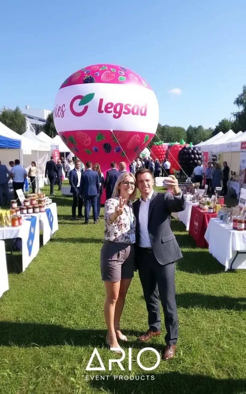 Balon reklamowy Legsad z nadrukiem owoców Balon pneumatyczny Legsad z nadrukiem owoców, w tle stoiska imprezy plenerowej.