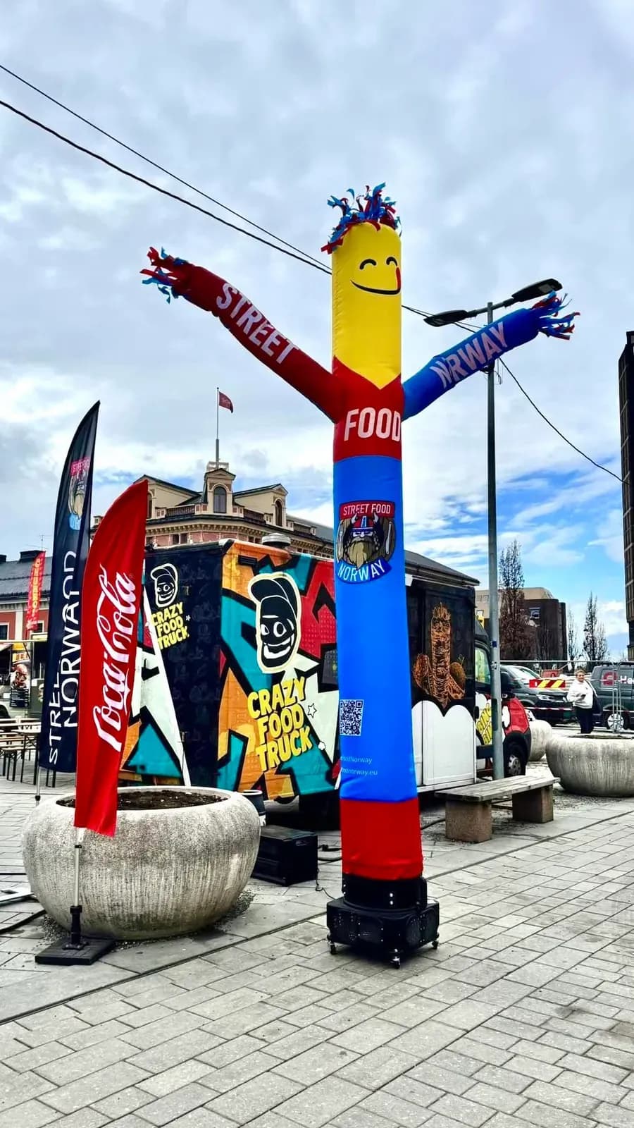 Chwiej reklamowy z napisem STREET FOOD na miejskim rynku w Norwegii, obok flagi reklamowe.
