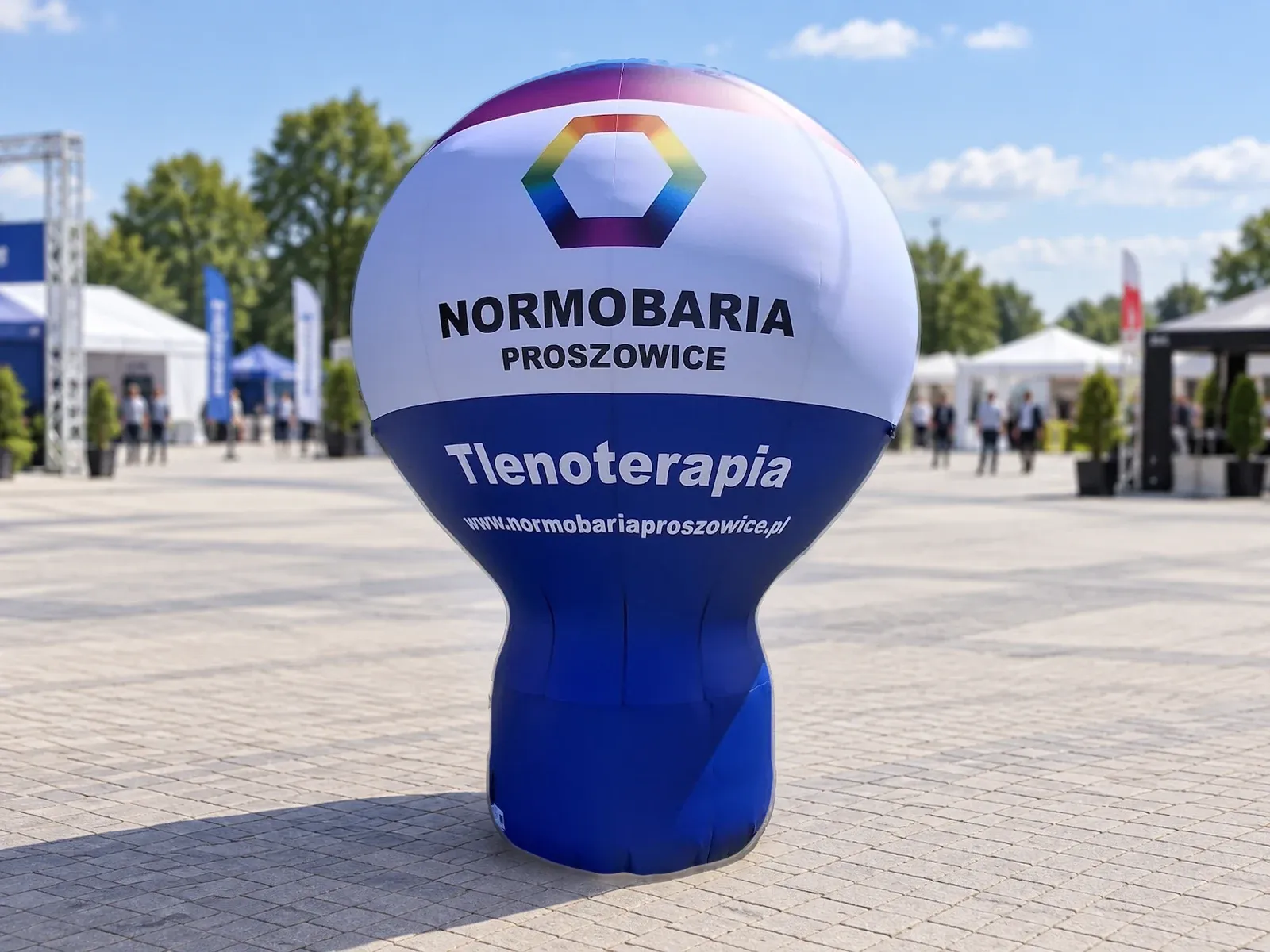 Balon reklamowy pneumatyczny z nadrukiem w barwach marki Normobaria Proszowice – produkt ARIO, tło wygenerowane przez AI